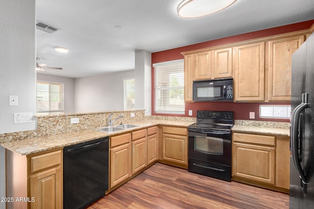 kitchen featuring black appliances, a sink, wood finished floors, and plenty of natural light