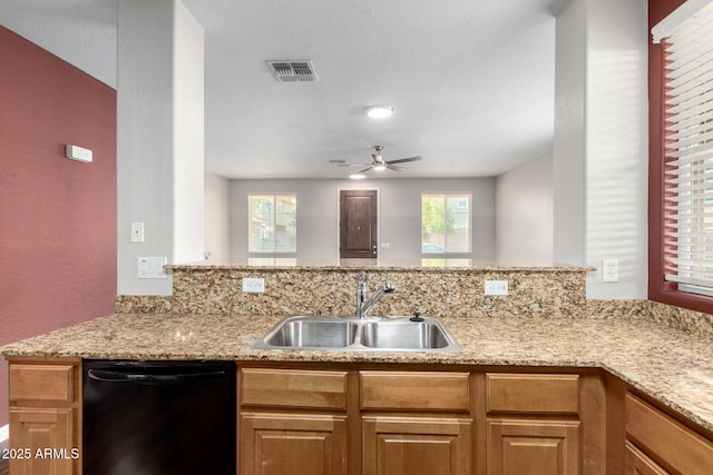kitchen featuring a sink, black dishwasher, a ceiling fan, and light stone counters