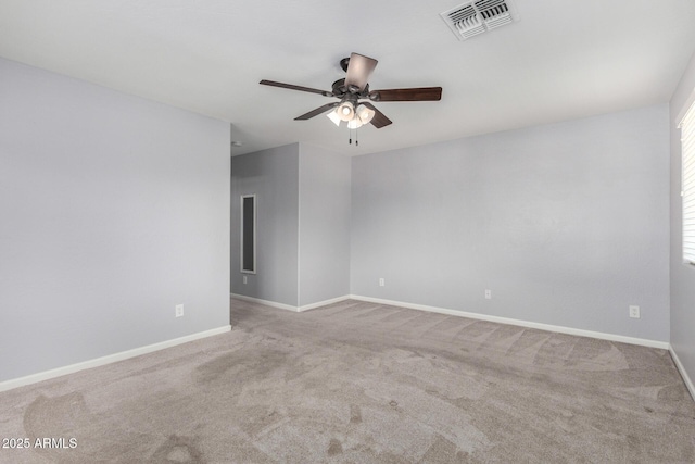 carpeted spare room featuring a ceiling fan and baseboards