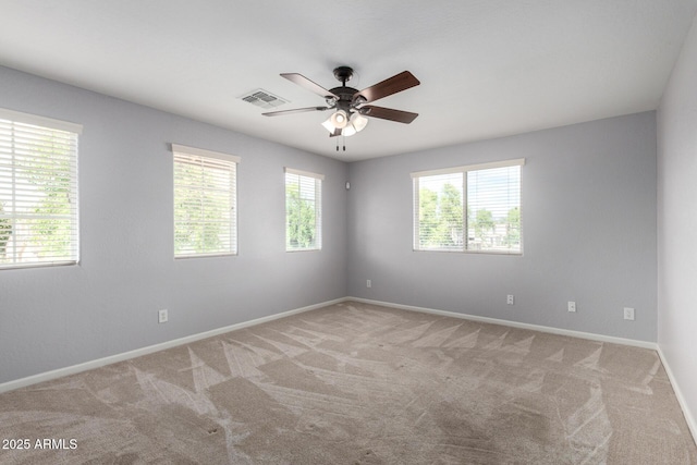 spare room featuring plenty of natural light, light colored carpet, a ceiling fan, and baseboards