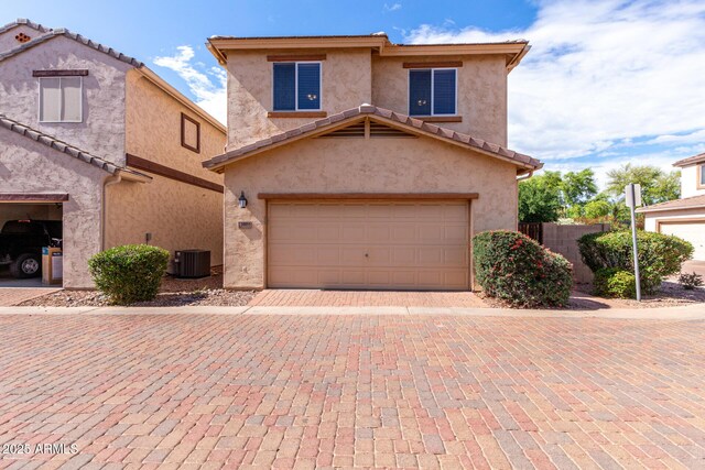 view of front of home featuring driveway, stucco siding, central AC unit, and a garage
