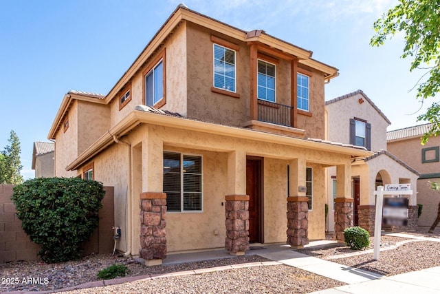 view of front of home featuring stucco siding, fence, and stone siding