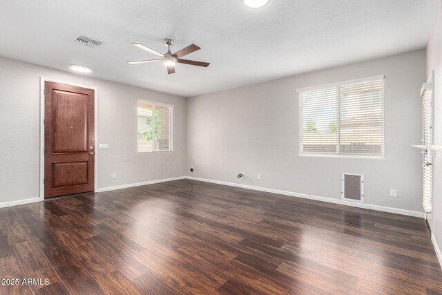 spare room featuring ceiling fan, dark wood finished floors, and baseboards