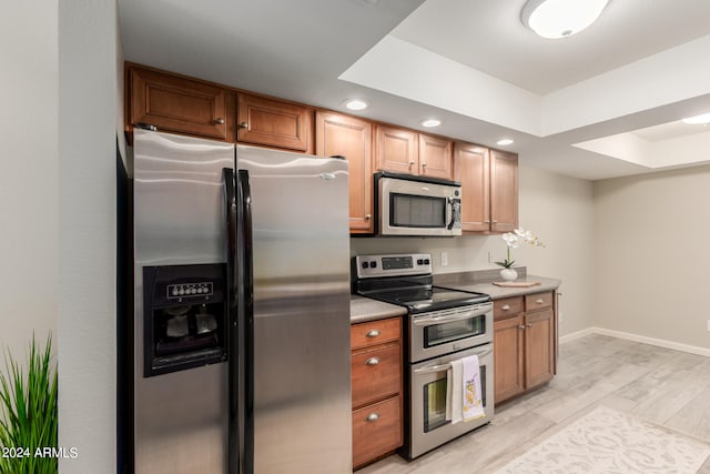 kitchen featuring appliances with stainless steel finishes, a raised ceiling, and light hardwood / wood-style floors