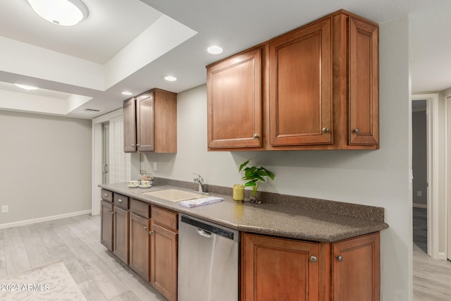 kitchen featuring dishwasher, light wood-type flooring, a raised ceiling, and sink