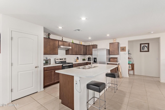 1617 W Pima Ct, Coolidge, AZ 85128 - kitchen with appliances with stainless steel finishes, under cabinet range hood, a kitchen bar, light countertops, and light tile patterned flooring