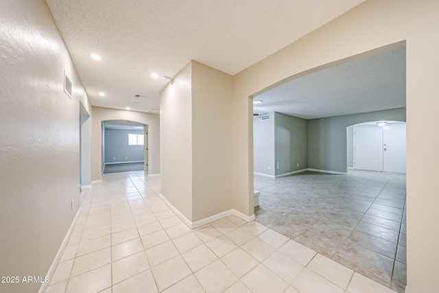 7439 E Ed Rice Ave, Mesa, AZ 85208 - corridor with arched walkways, a textured ceiling, light tile patterned floors, recessed lighting, and baseboards
