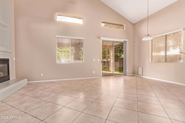 21373 N 94th Ave, Peoria, AZ 85382 - unfurnished living room with light tile patterned floors, high vaulted ceiling, baseboards, and a glass covered fireplace