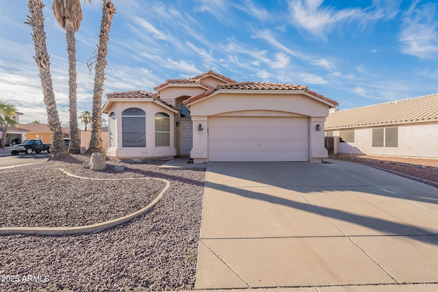 mediterranean / spanish-style house featuring a garage, concrete driveway, a tiled roof, and stucco siding