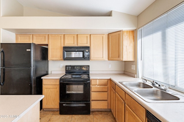 kitchen featuring lofted ceiling, a sink, light countertops, light brown cabinetry, and black appliances