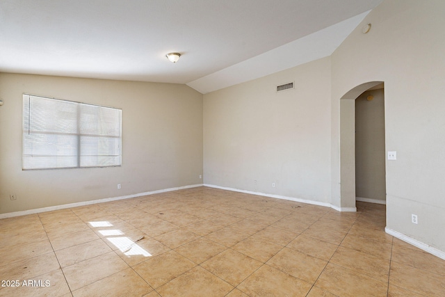 spare room featuring lofted ceiling, light tile patterned floors, arched walkways, visible vents, and baseboards