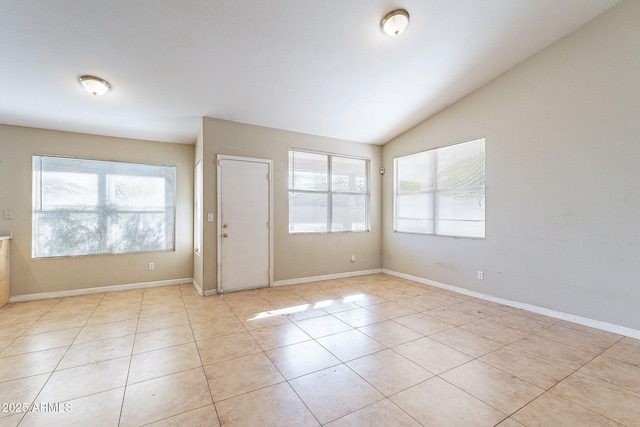 unfurnished room featuring light tile patterned floors, lofted ceiling, and baseboards