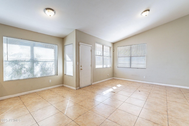 interior space featuring baseboards, vaulted ceiling, and light tile patterned flooring