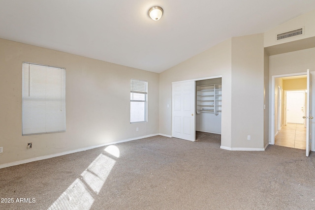 unfurnished bedroom with carpet floors, a closet, visible vents, vaulted ceiling, and baseboards