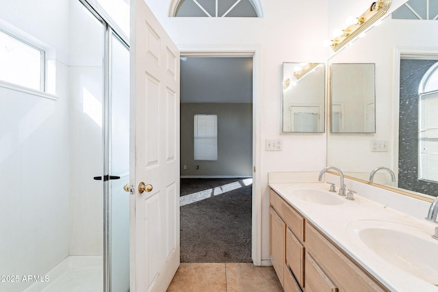 bathroom featuring tile patterned flooring, an enclosed shower, a sink, and double vanity