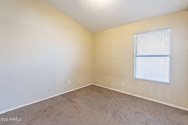 carpeted spare room with vaulted ceiling and baseboards