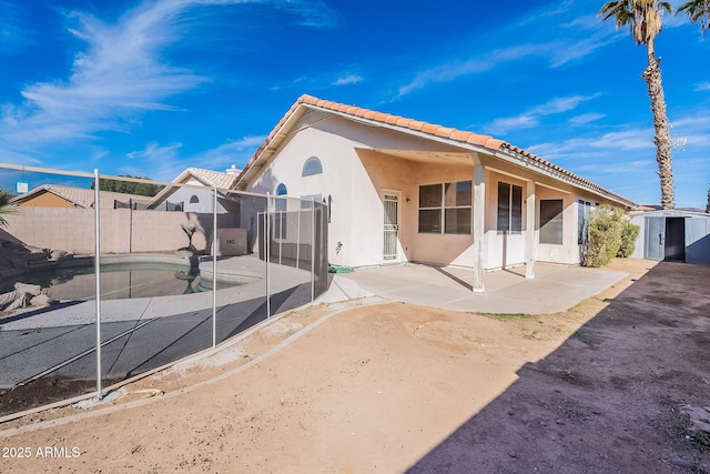 back of property with a patio area, an outdoor structure, a storage shed, and stucco siding