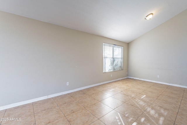 unfurnished room featuring lofted ceiling, tile patterned flooring, and baseboards