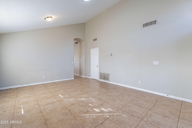 tiled spare room with arched walkways, visible vents, and baseboards