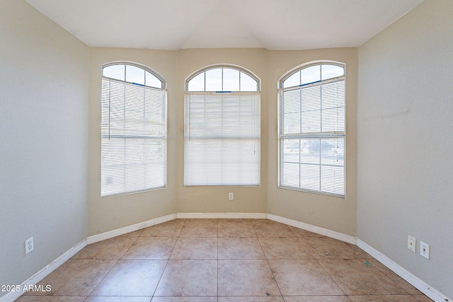 unfurnished room featuring baseboards and a wealth of natural light