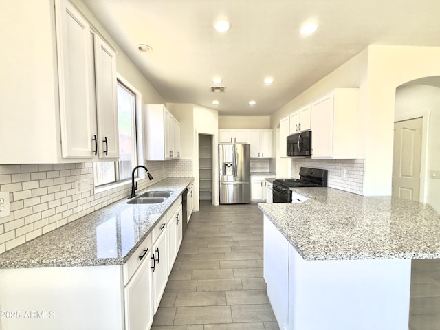 7116 W Sophie Ln, Laveen, AZ 85339 - kitchen featuring black appliances, a sink, a peninsula, light stone counters, and white cabinets