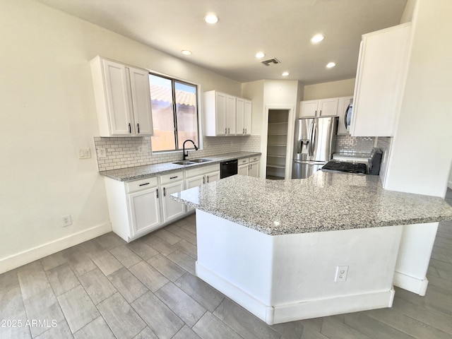 7116 W Sophie Ln, Laveen, AZ 85339 - kitchen featuring stainless steel appliances, a peninsula, light stone countertops, white cabinets, and recessed lighting
