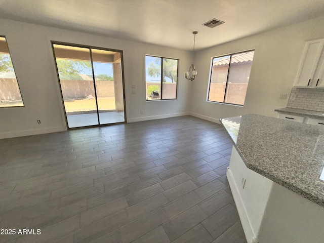 7116 W Sophie Ln, Laveen, AZ 85339 - unfurnished dining area with plenty of natural light, baseboards, and a chandelier