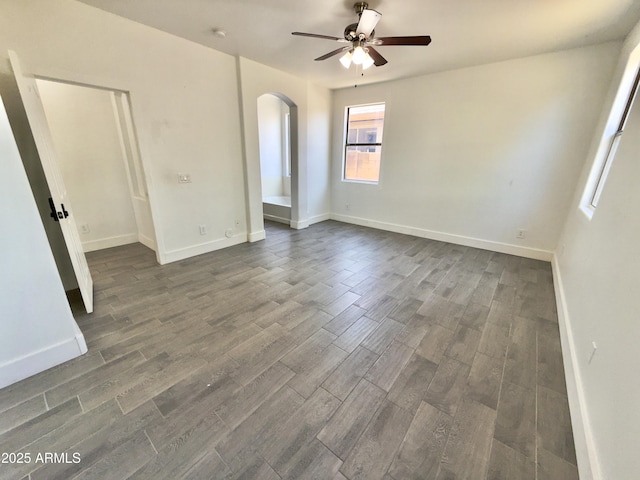 7116 W Sophie Ln, Laveen, AZ 85339 - spare room with arched walkways, a ceiling fan, dark wood-style floors, and baseboards