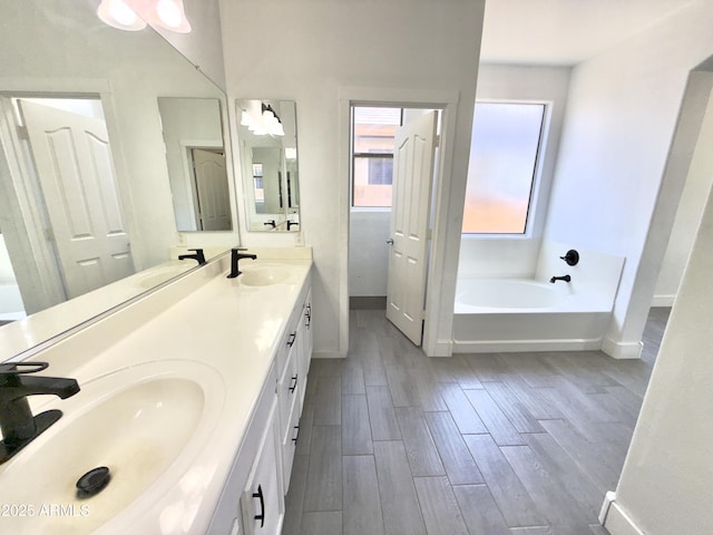7116 W Sophie Ln, Laveen, AZ 85339 - full bathroom with wood finished floors, double vanity, a garden tub, and baseboards