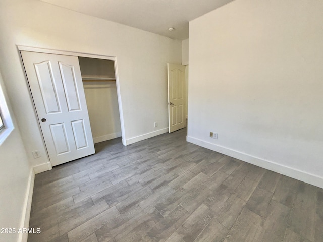 7116 W Sophie Ln, Laveen, AZ 85339 - unfurnished bedroom featuring dark wood finished floors, a closet, and baseboards