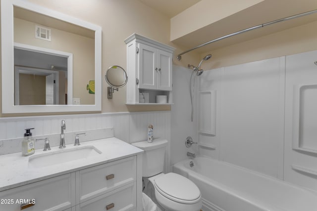 full bathroom featuring toilet, vanity, visible vents, wainscoting, and tub / shower combination