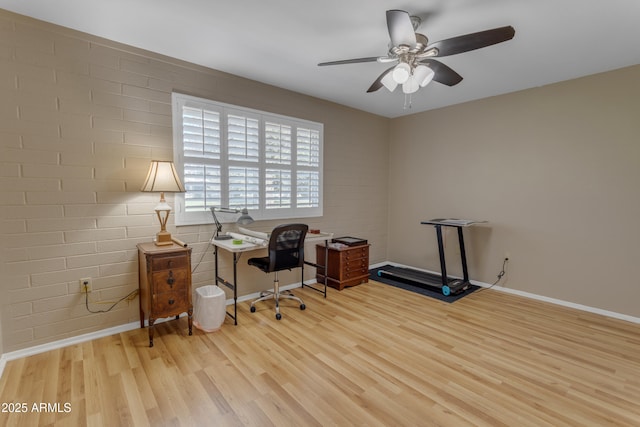 office area featuring a ceiling fan, brick wall, baseboards, and wood finished floors