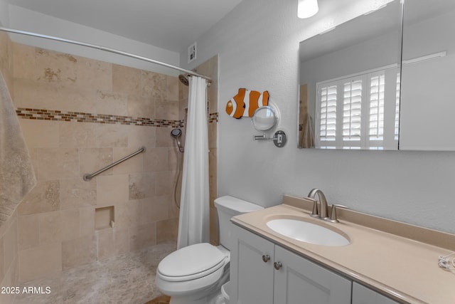 full bath featuring toilet, a tile shower, and vanity