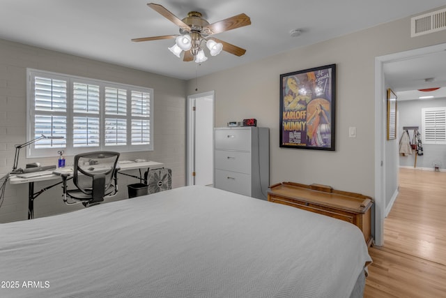 bedroom with light wood-type flooring, visible vents, ceiling fan, and baseboards