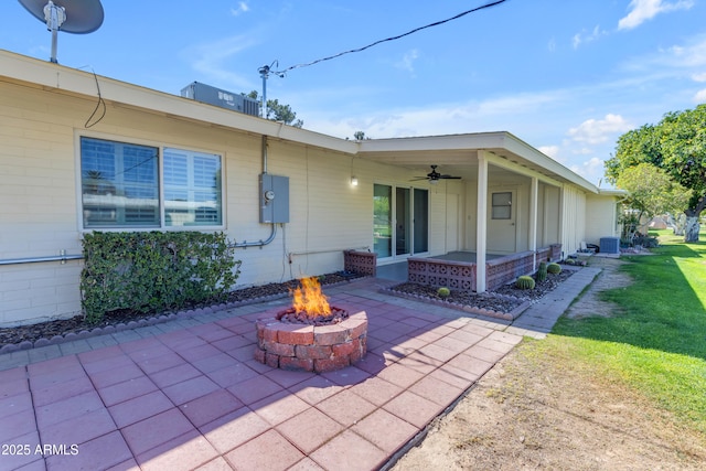 back of property with ceiling fan, an outdoor fire pit, cooling unit, a yard, and a patio area