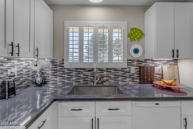 kitchen with white dishwasher, white cabinets, and a sink