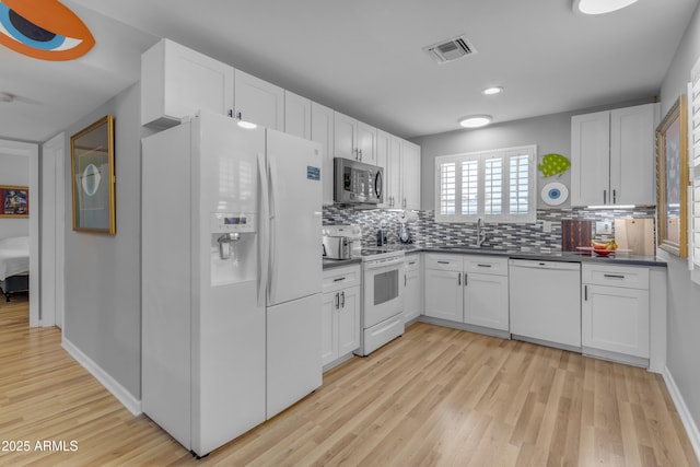 kitchen featuring white appliances, visible vents, white cabinets, decorative backsplash, and dark countertops