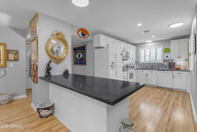 kitchen with white appliances, visible vents, white cabinets, light wood-type flooring, and backsplash