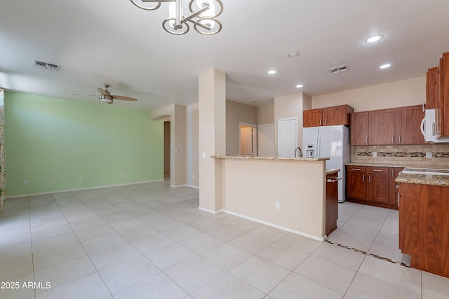 kitchen featuring visible vents, light tile patterned flooring, white appliances, and tasteful backsplash