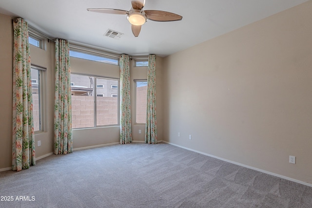 unfurnished room with visible vents, a ceiling fan, and carpet flooring