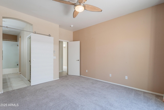 unfurnished bedroom featuring baseboards, a ceiling fan, connected bathroom, and light colored carpet