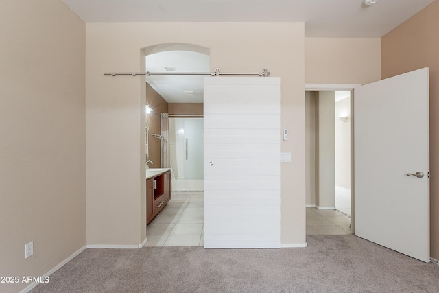 unfurnished bedroom featuring baseboards, light colored carpet, and ensuite bath