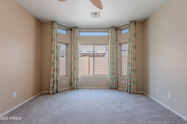spare room featuring carpet floors, a ceiling fan, baseboards, and visible vents
