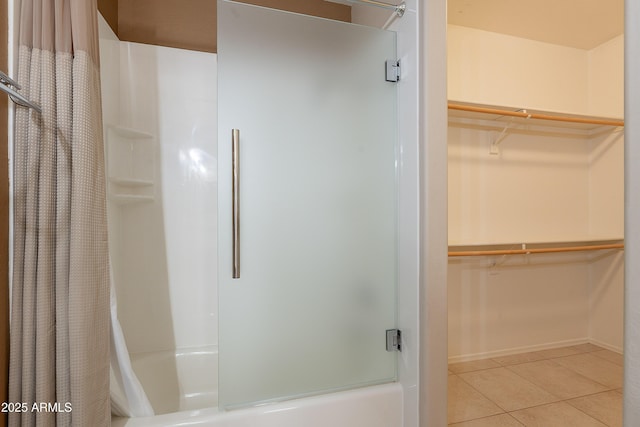 full bath with bath / shower combo with glass door, tile patterned floors, and a walk in closet