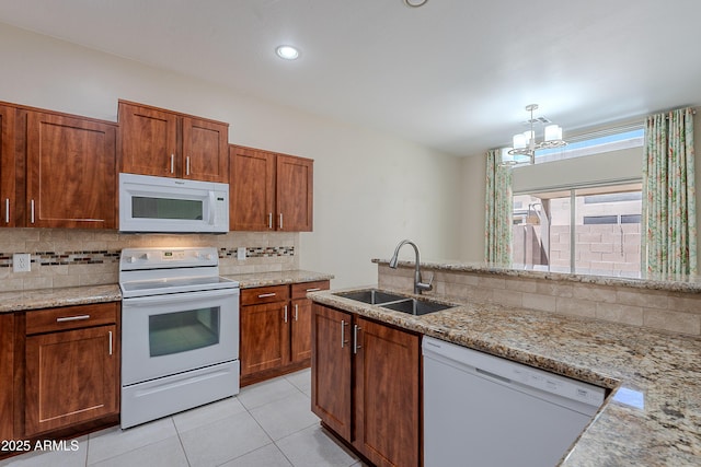 kitchen with decorative backsplash, light stone countertops, a sink, a notable chandelier, and white appliances