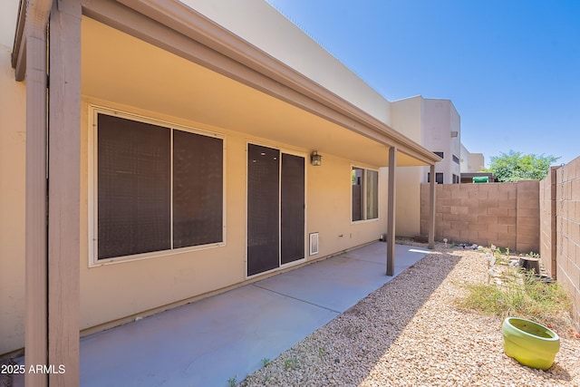 rear view of house with fence, a patio, and stucco siding