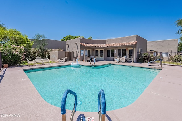pool with fence, a patio area, and french doors
