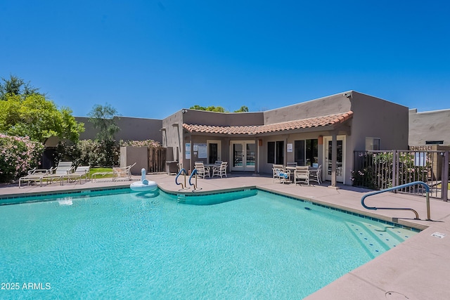 pool with a patio area, fence, and french doors