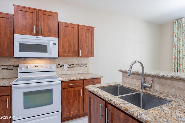 kitchen with white appliances, backsplash, light stone counters, and a sink
