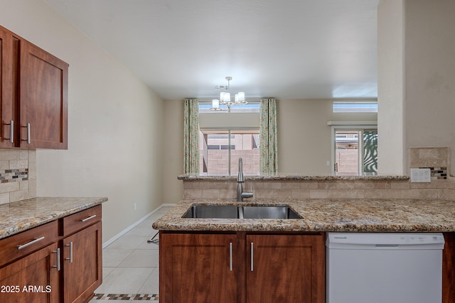 kitchen featuring backsplash, light stone countertops, a sink, and dishwasher
